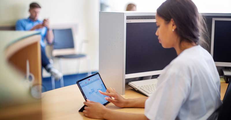 woman sitting at desk using digital tablet
